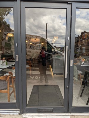 Glass door with grey frame and silver handle. Push to open.