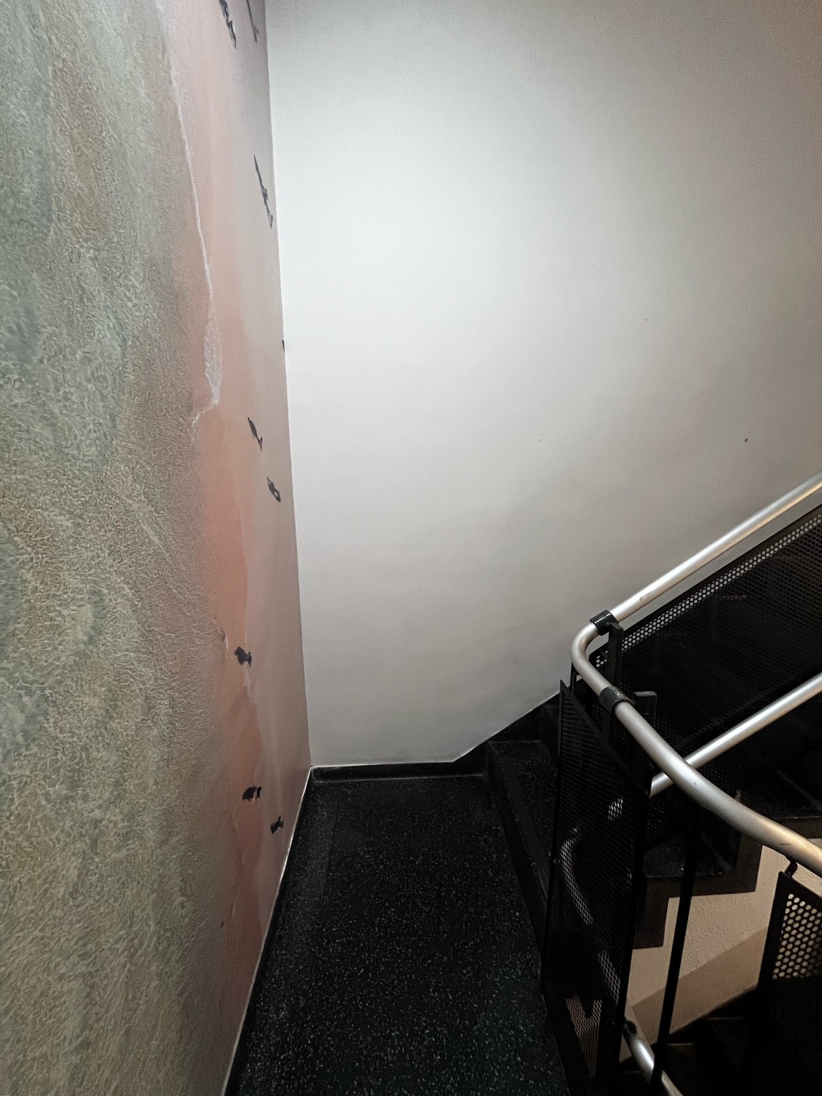 From top of first flight of stairs, facing right. Landing ahead. Silver handrail on right.