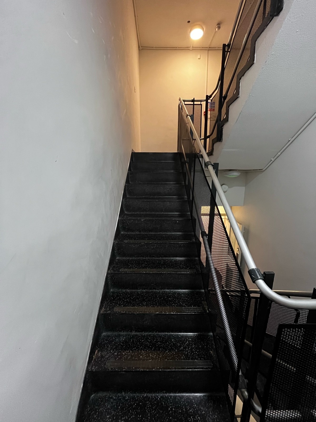 From end of landing, facing right. Second flight of stairs ahead. White handrail along right.