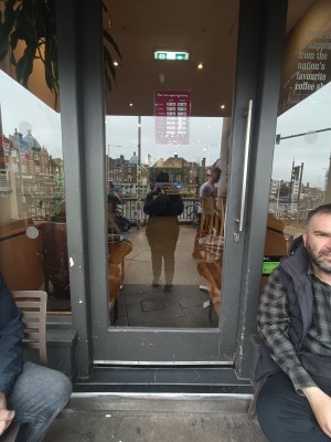 Glass door with grey wooden frame, push silver handle on right to open.