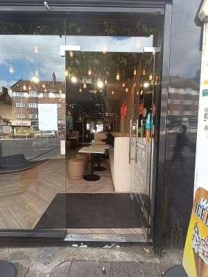 Glass door with silver handle on left, push to open.