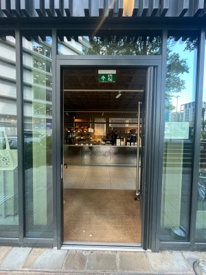Glass door with black frame. Push silver handle on left to open.