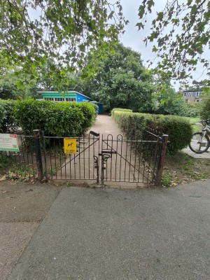 From park facing venue. Preceding metal half gates ahead. Push or pull from centre to open.