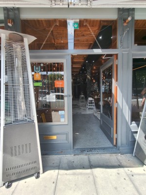 Grey framed glass doors. Push silver handle on left of right door to open.