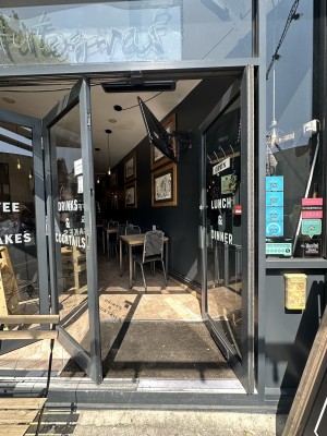 Glass door with black frame. Push silver handle from left to open. Sliding glass wall to left are open during summer months.