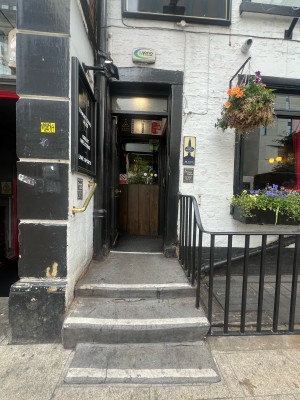 Preceding black door ahead. Push from knob on right to open. Metal handrails along left and right.