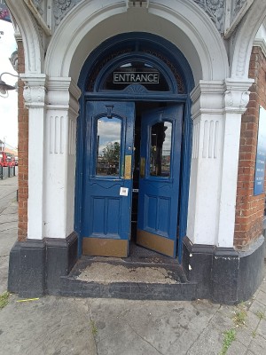 Glass door with blue, wooden frame ahead. Push from middle to open.