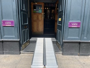 Silver ramp leads above steps. Second preceding double doors ahead. Pull from metal handles in centre to open.
