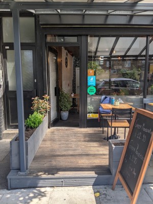Step up with metal frame and planters on booths both sides. A-frame sign on right.