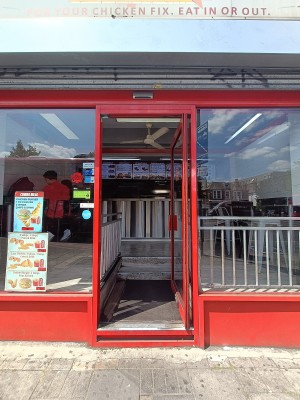 Glass door with red, metal frame. Push from left to open.