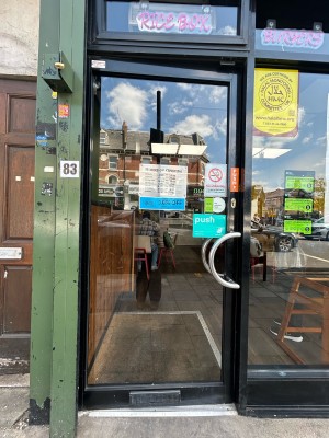 Glass door ahead with black frame. Silver handle on right, push to open.