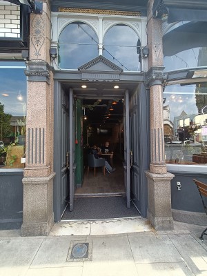 Glass doors with grey, wooden frames ahead. Pull golden handles from middle to open.