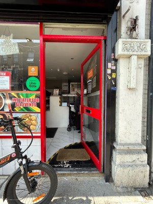 Glass door with red frame. Push red handle on left to open.