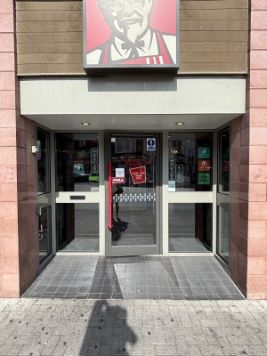 Opening ahead. Glass door with metal frame on back. Pull door to open via red handle on left.