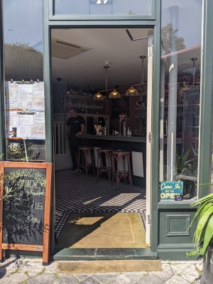 Glass door with green frame. Push from metal handle on left to open.