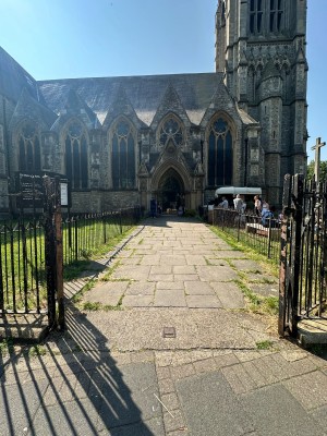 From pavement facing venue. Opening ahead. Path behind leads to second gate.