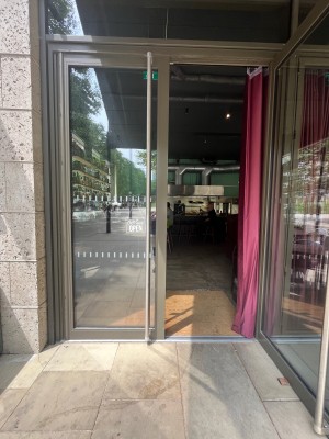 Glass double doors with black frame. Pull silver handle at centre of door to open. Red curtain on right side of door.