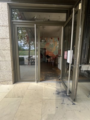 Glass double doors with black metal frame. Pull silver handle on left of right door to open.