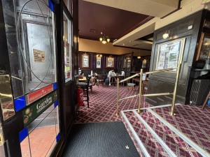 From glass doors in main entrance, facing left. Stairs along right, handrail on back right. Opening ahead to side area.