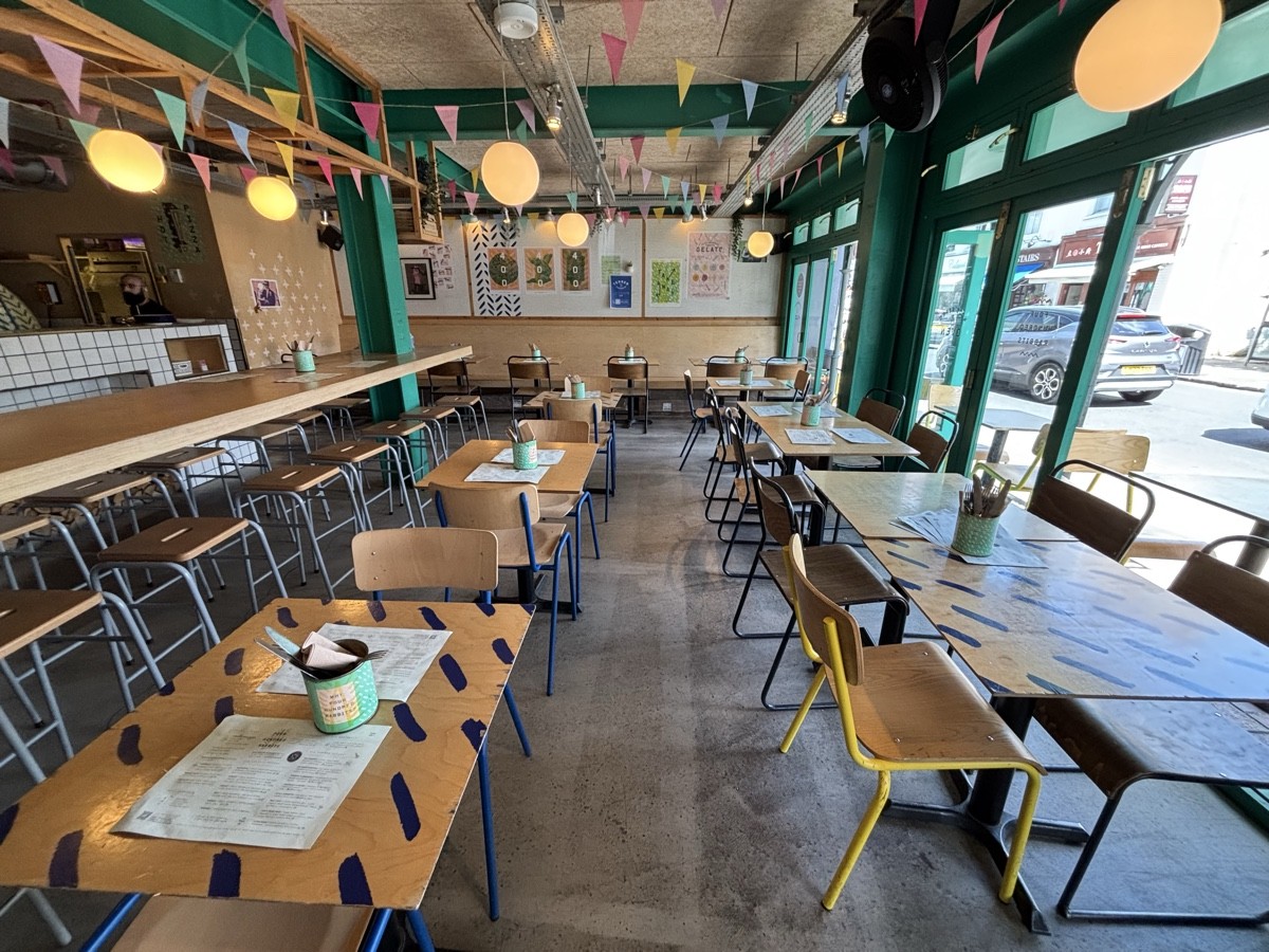From entrance facing right. Tables and chairs along left and right. High table and stools on the far left.