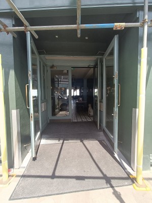 Glass doors with green, wooden frame ahead. Pull golden handles in middle to open.