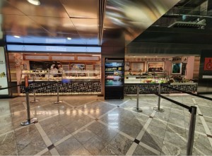 From walkway facing venue. Restaurant barriers ahead lead to counter along back.