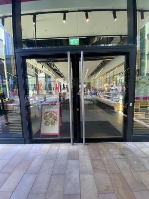 Glass doors with black frames ahead. Pull from metal handles in centre to open