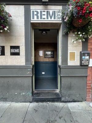 Grey preceding door with grey handle. Push handle on left of door to open.