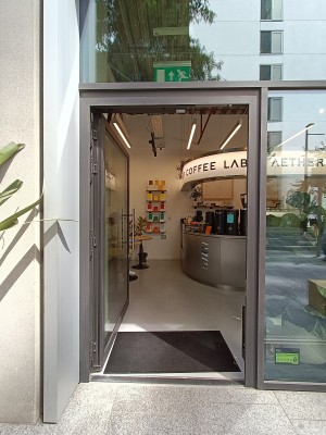 Glass door with grey, metal frame. Push silver handle on right to open.