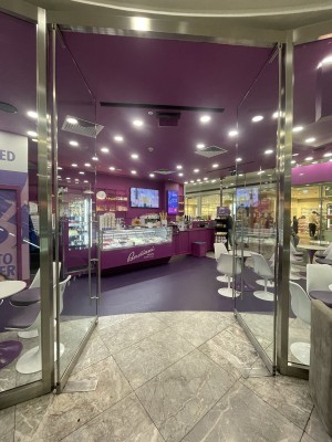 From street facing venue. Glass doors ahead. Push silver metal handles from centre to open.