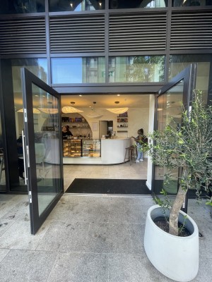 Glass doors with black frame ahead. Pull silver metal handles from centre to open. Planter on right.
