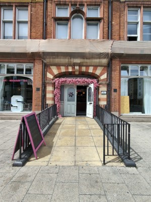 Built-in ramp going up to entrance doors at back. Black handrails along left and right.