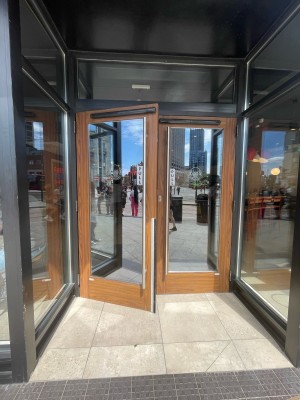 Facing glass paneled doors with wooden frames. Pull in center to open.