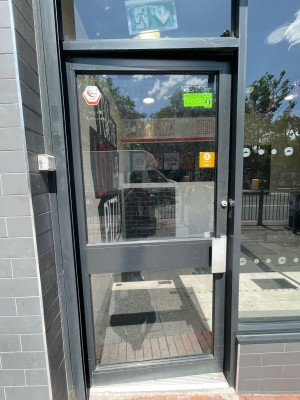 Facing glass paneled door with gray frame. Push on right to open.