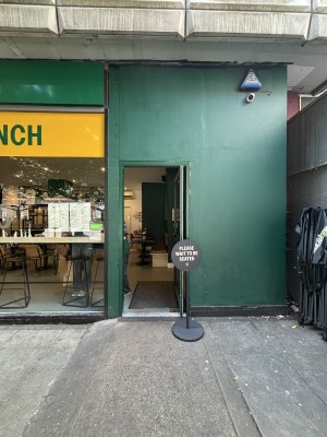 Glass door with green frame ahead. Push from left to open.