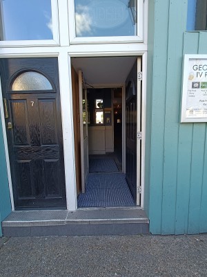 Black, wooden door ahead. Push from left to open.
