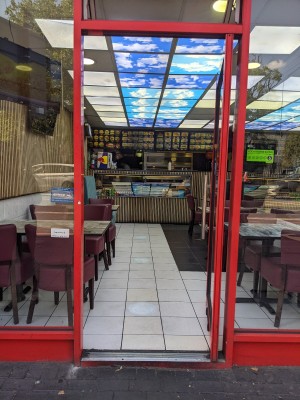 Glass door with red frame and silver handle. Push from left to open.