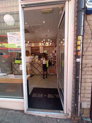 Glass door with white, wooden frame ahead. Push from left to open.