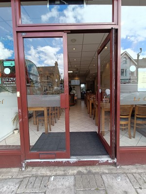 Glass door with red, metal frame ahead. Push from middle to open.
