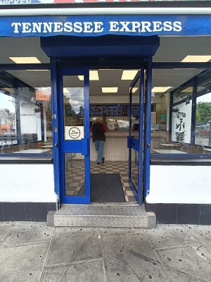 Glass door with blue, metal frame ahead. Push from middle to open.