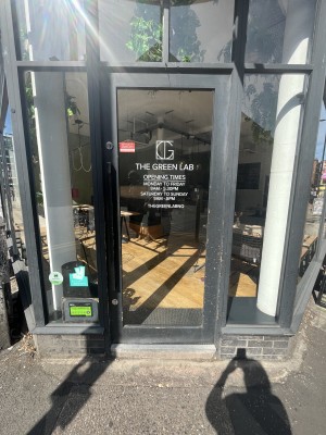 Glass door with black frame and black handle. Push handle on right of door to open.