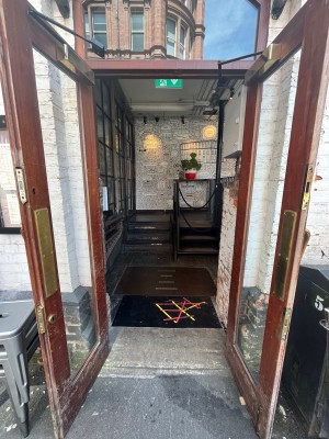 Preceding double glass doors with red frames and gold handle. Pull handle in centre of doors to open. Doormat follows.