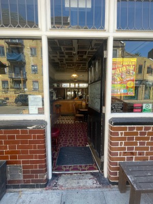 Black glass and wooden door ahead. Push gold metal handle on left to open.