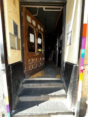 3 steps up to wooden preceding single door. Push from handle on right to open.