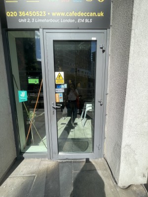 Glass door with grey frame ahead. Push grey metal handle from left to open.