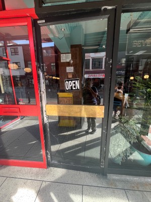 Glass door with black frame. Push on left of door to open.
