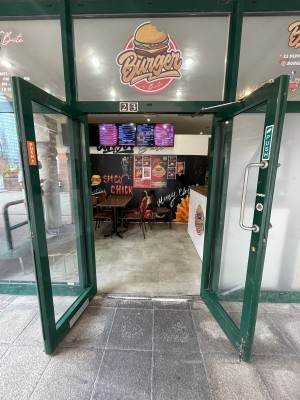 Glass doors with green frame ahead. Pull silver metal handle from centre to open.