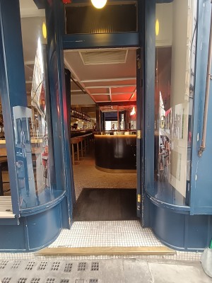 Glass door with blue, wooden frame ahead. Push from left to open.