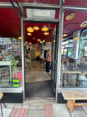 Glass door with black frame. Push handle on left to open.