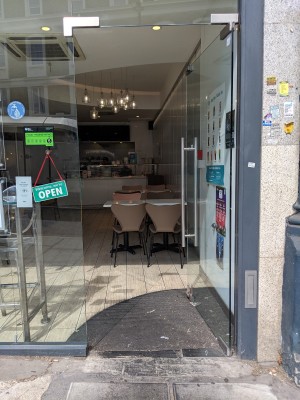 Glass door with silver handle on left. Push to open.